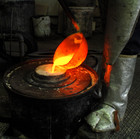 the liquid bronze being poured into a cylinder containing the wax model